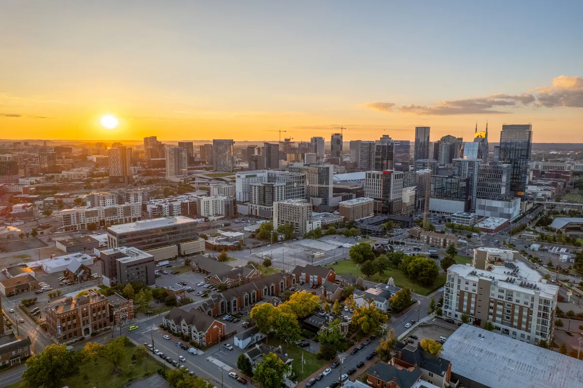 This image offers a sweeping view of the city skyline with the sun setting behind urban parks and historic buildings, evoking a sense of vibrant city life and the promise of romantic evenings out.
